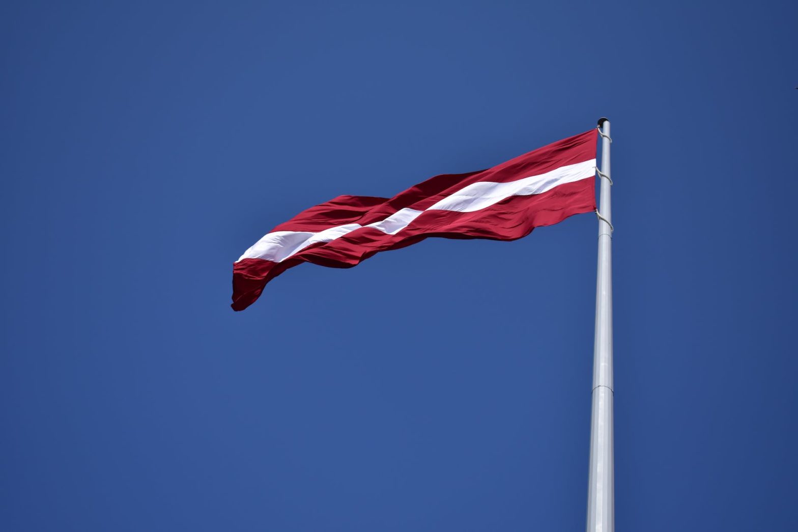 red and white state flag waving under blue sky at daytime